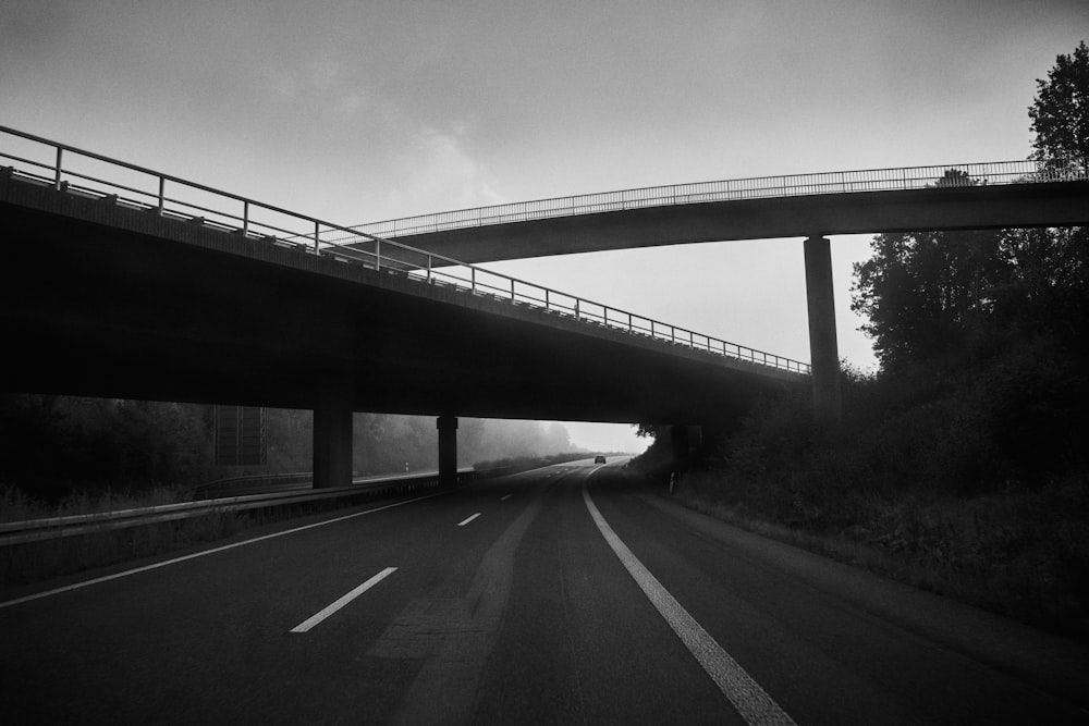 a black and white photo of a bridge over a road