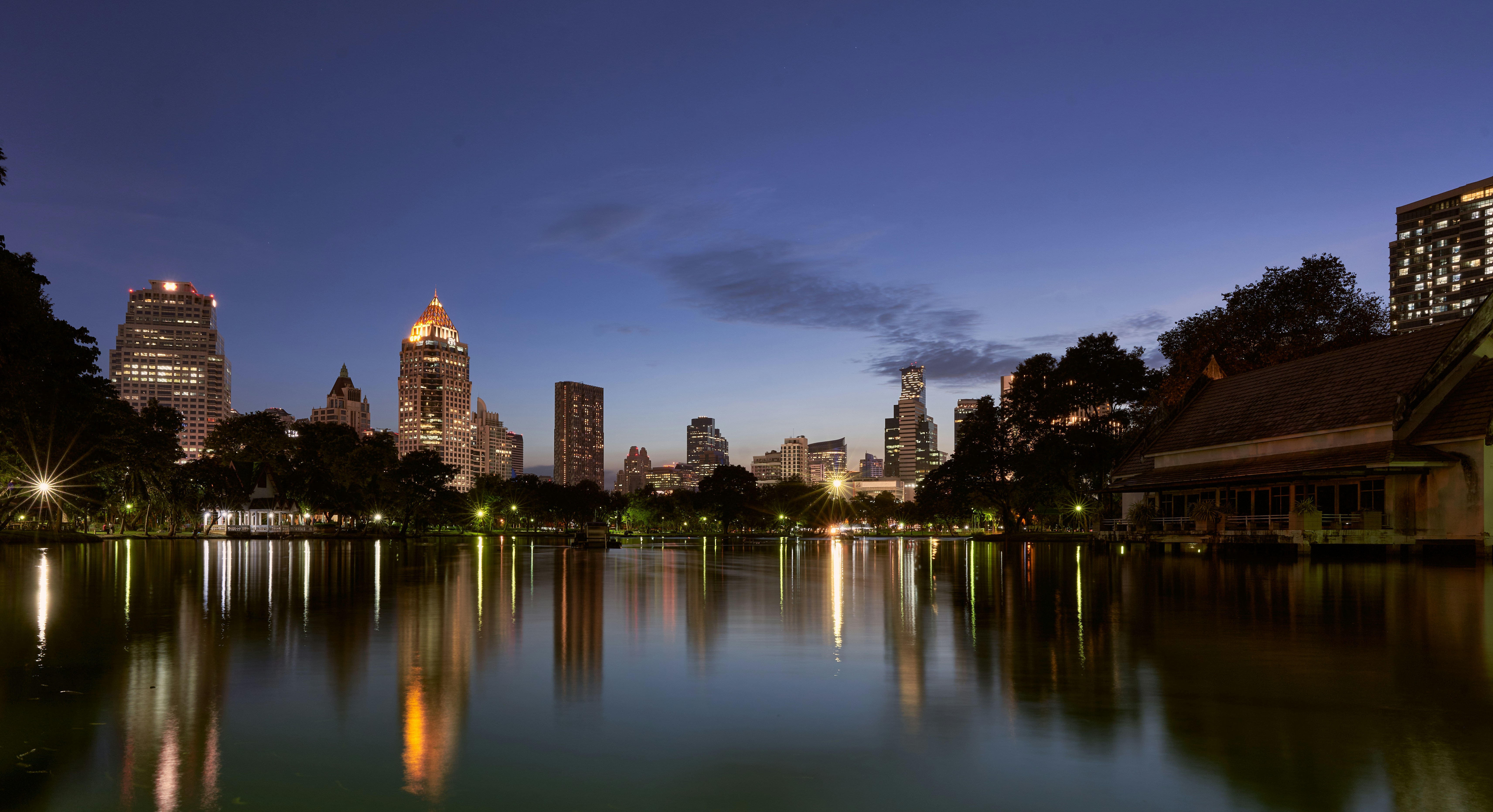 a view of a city at night from across a lake, Lumpini Park, Bangkok. Skyline at night, mirroring in the lake
