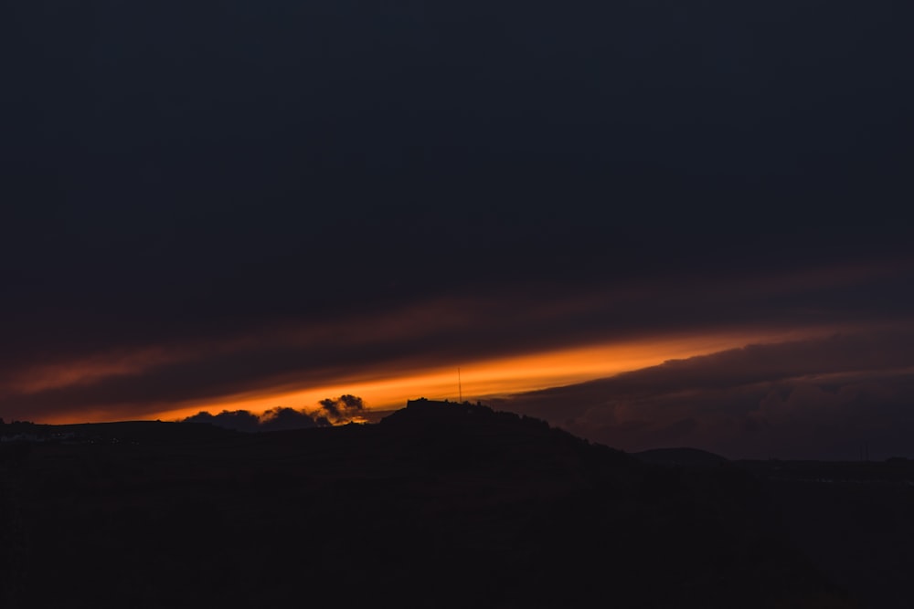 the sun is setting over a mountain with clouds