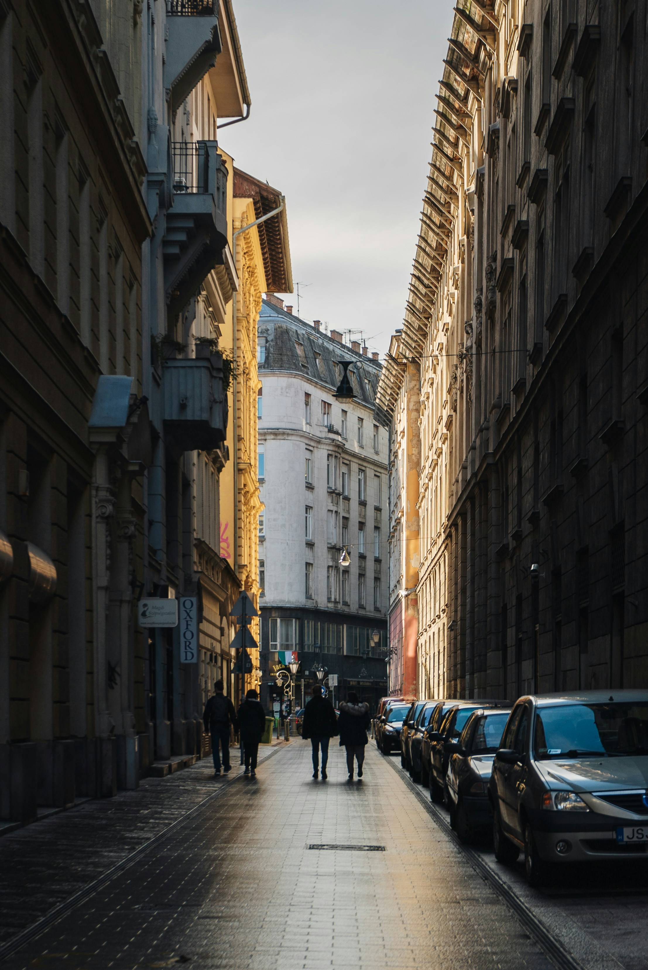 a group of people walking down a street next to tall buildings