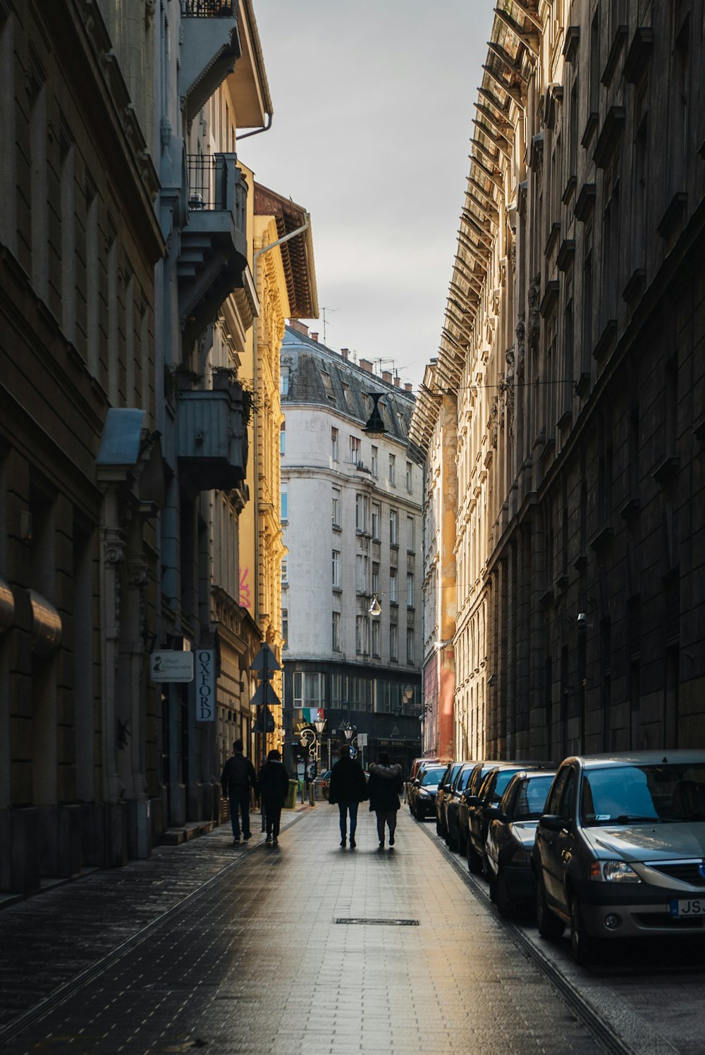 a group of people walking down a street next to tall buildings