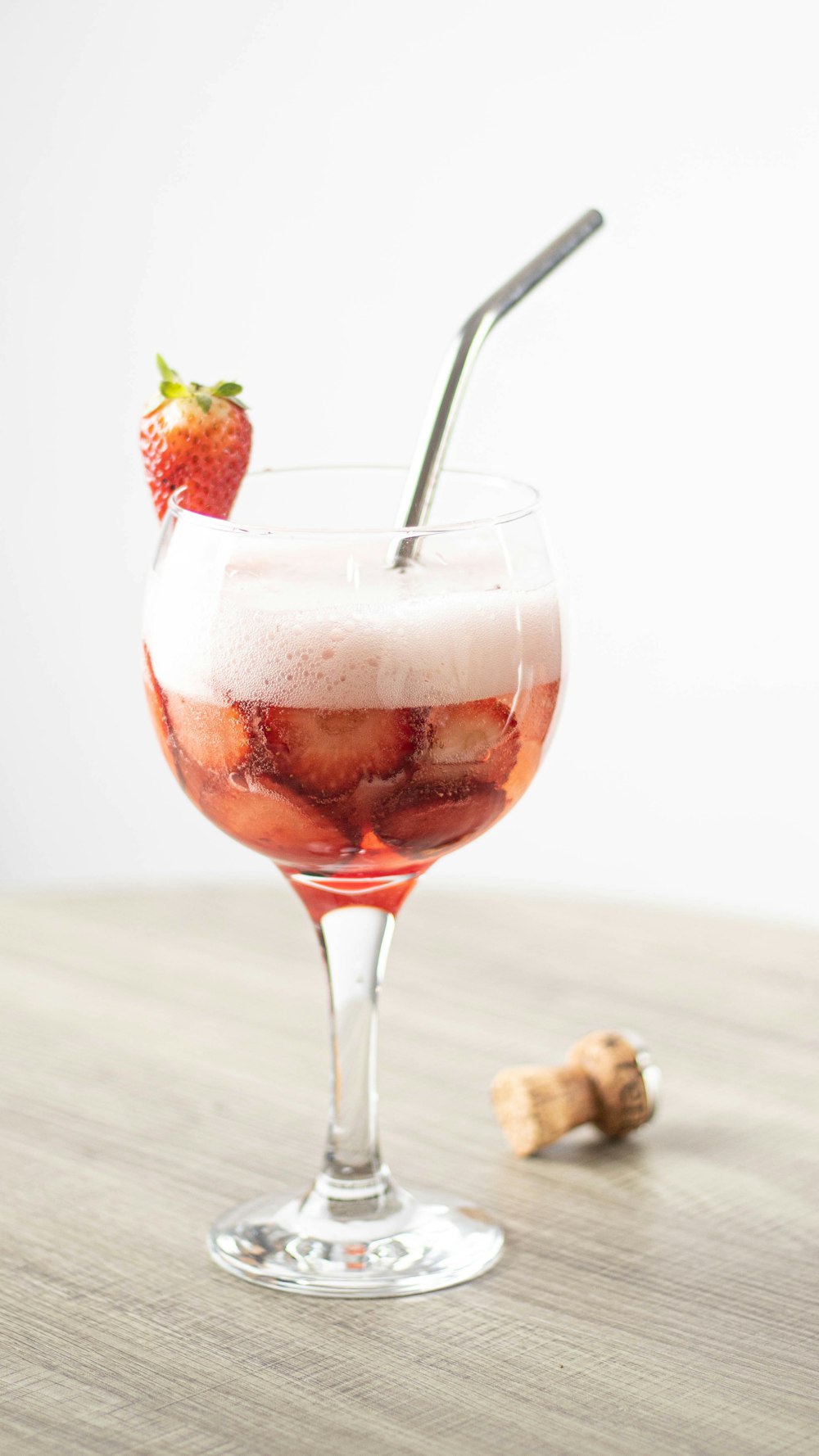a glass filled with liquid and a strawberries on top of it