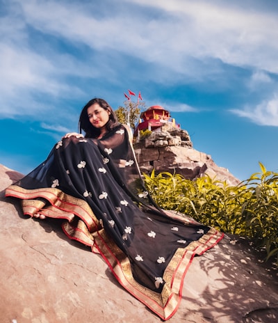 a woman sitting on top of a large rock