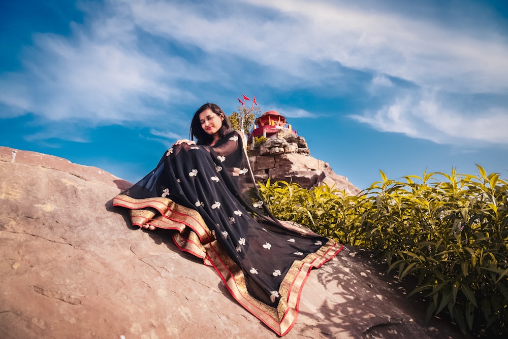 a woman sitting on top of a large rock