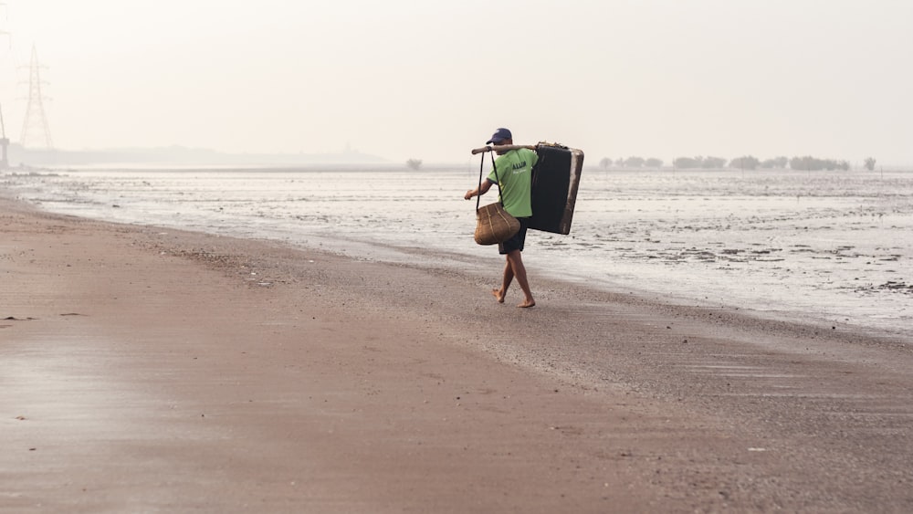 a man walking along a beach carrying a suitcase