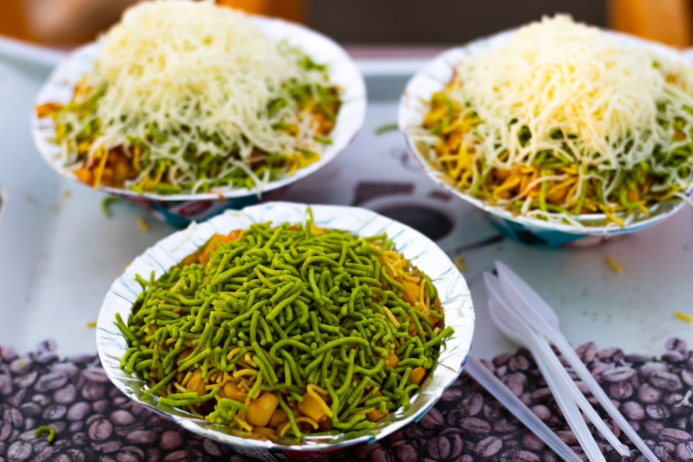 a table topped with three bowls filled with veggies