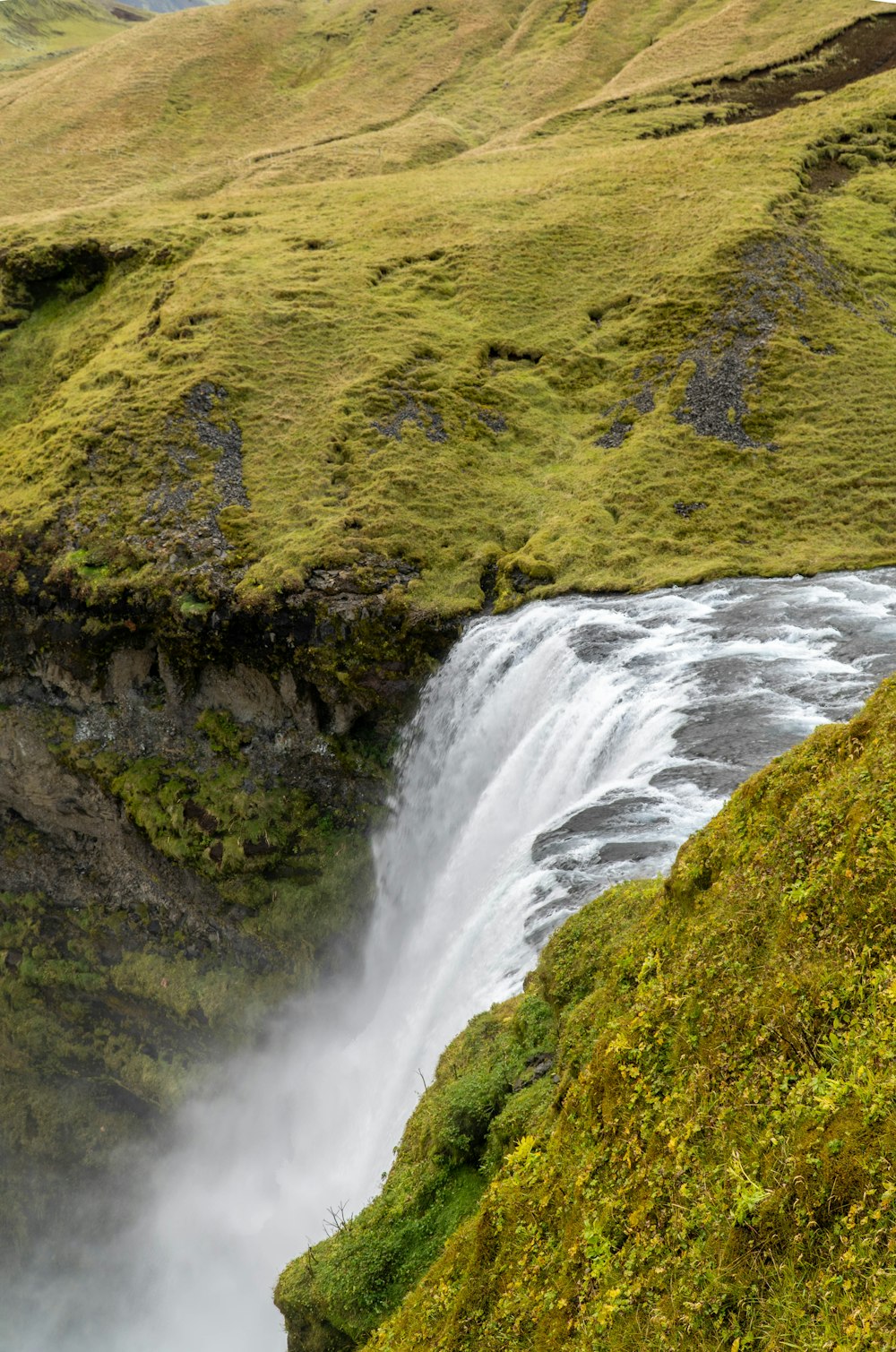 a waterfall in the middle of a lush green valley