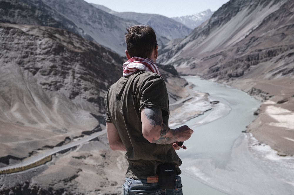 a man standing on top of a mountain next to a river