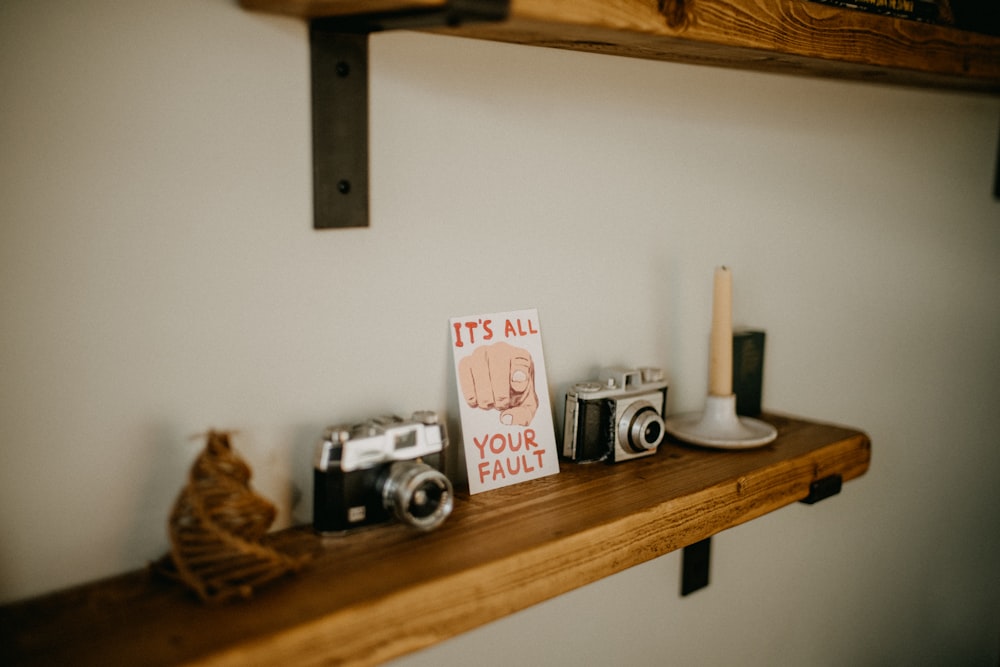 a couple of cameras sitting on top of a wooden shelf