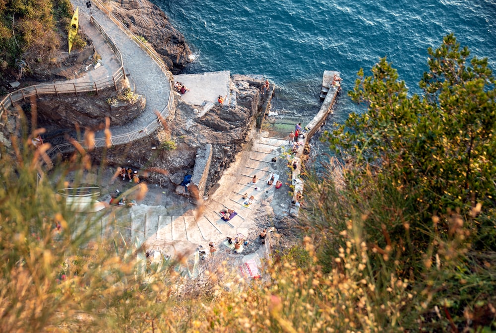 a group of people standing on top of a cliff next to a body of water
