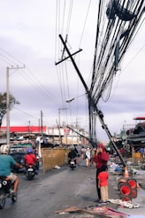 a group of people walking down a street next to power lines