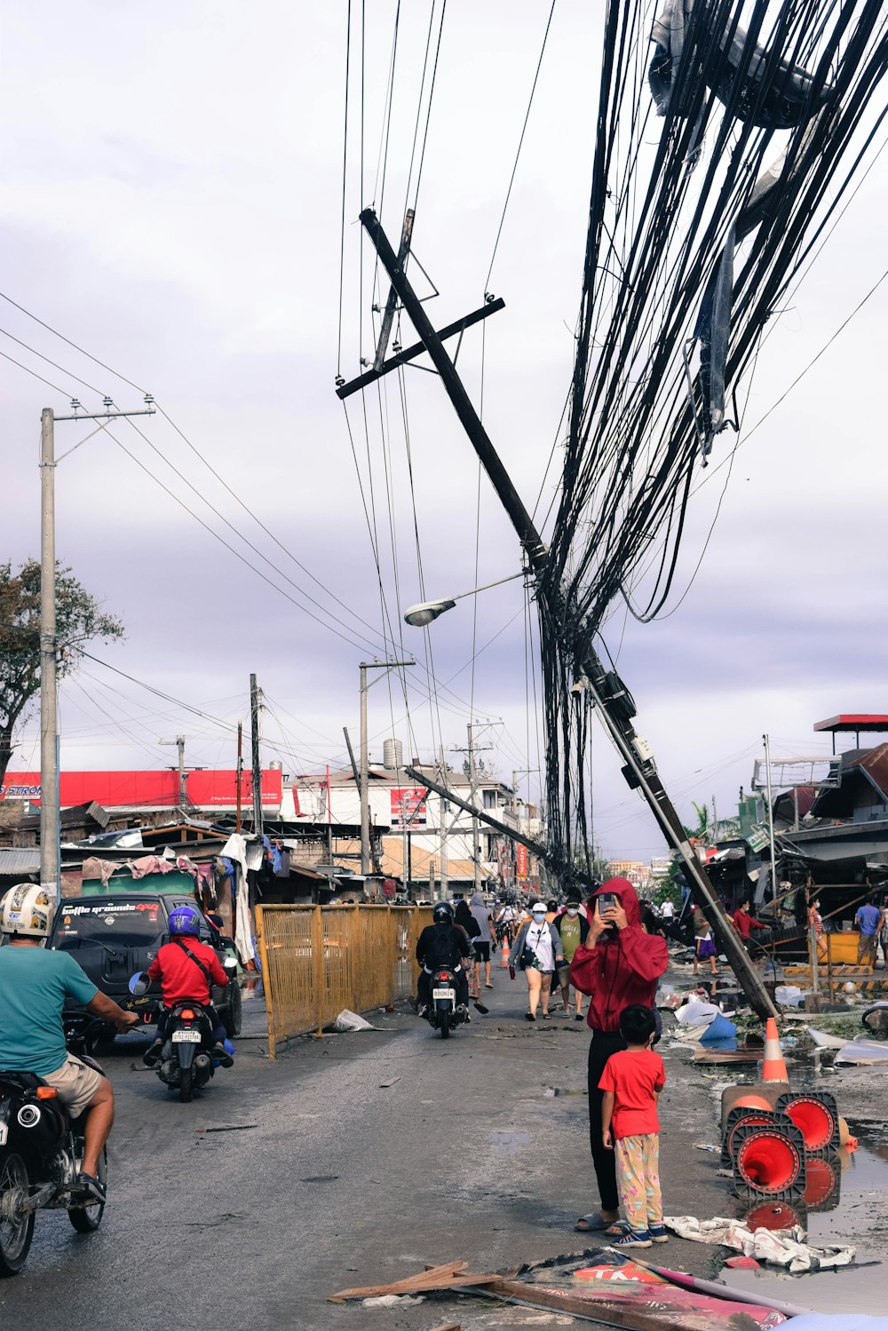 a group of people walking down a street next to power lines