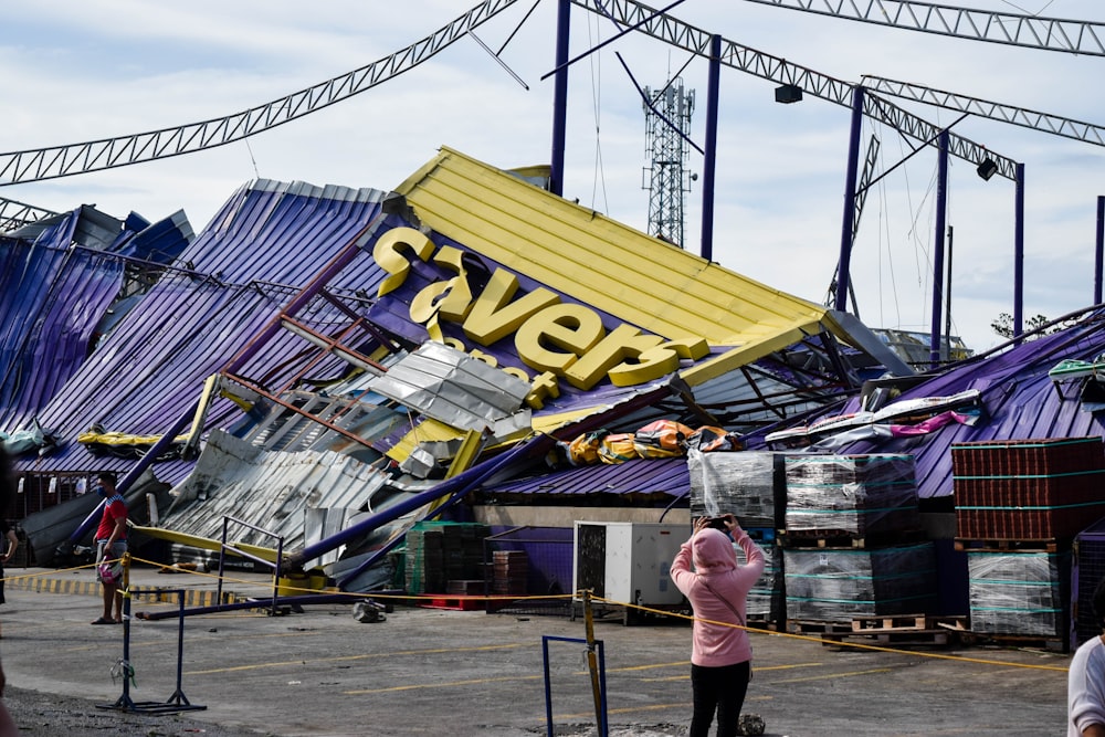 a woman standing in front of a building that has been blown over