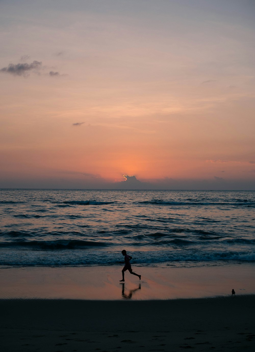 a person running on the beach at sunset