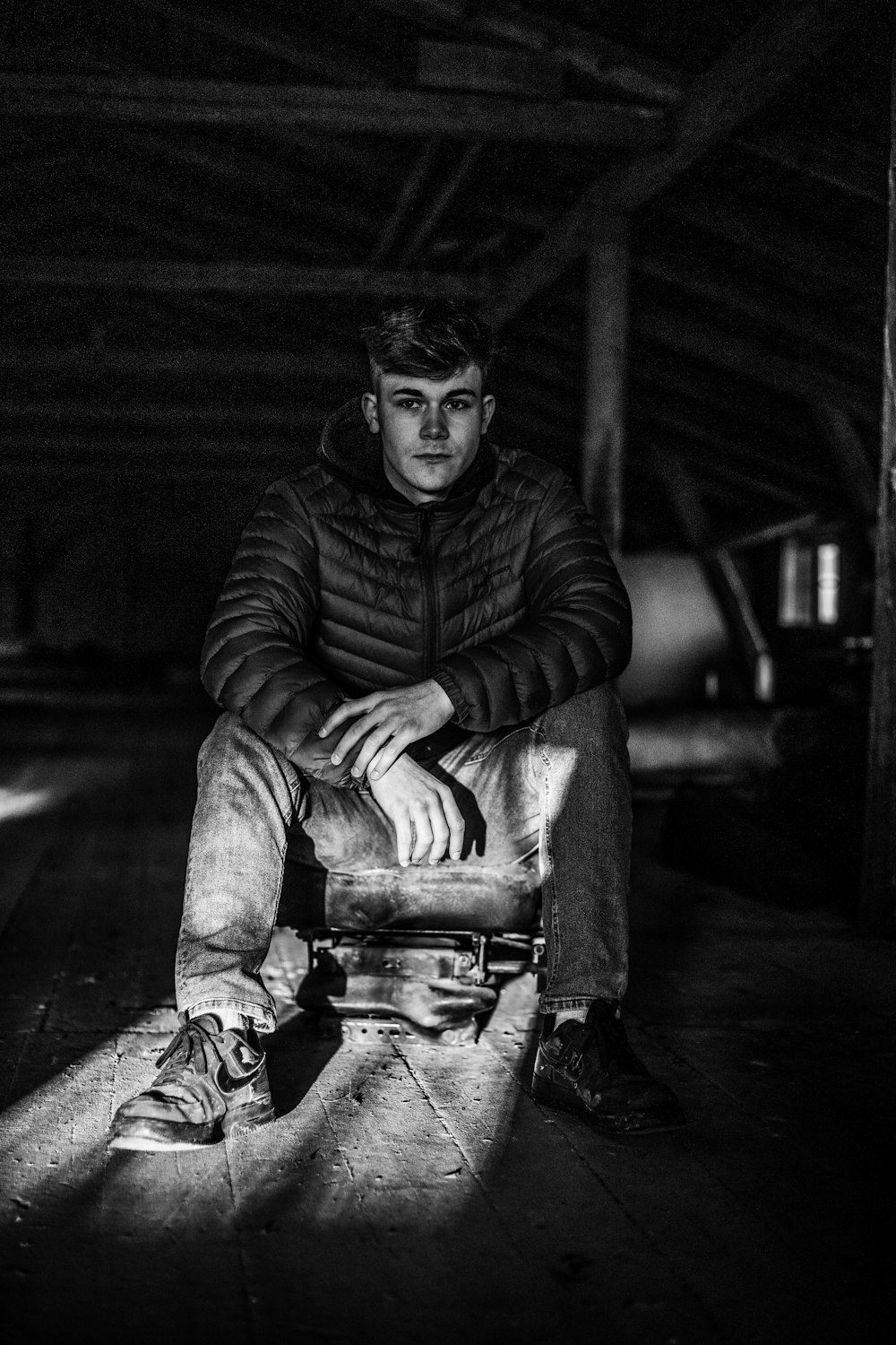 a black and white photo of a man sitting on a suitcase