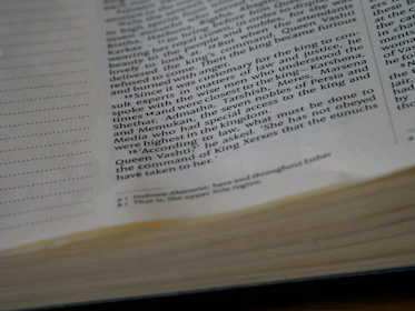 Close-up of hands flipping through a textbook with school logo visible.