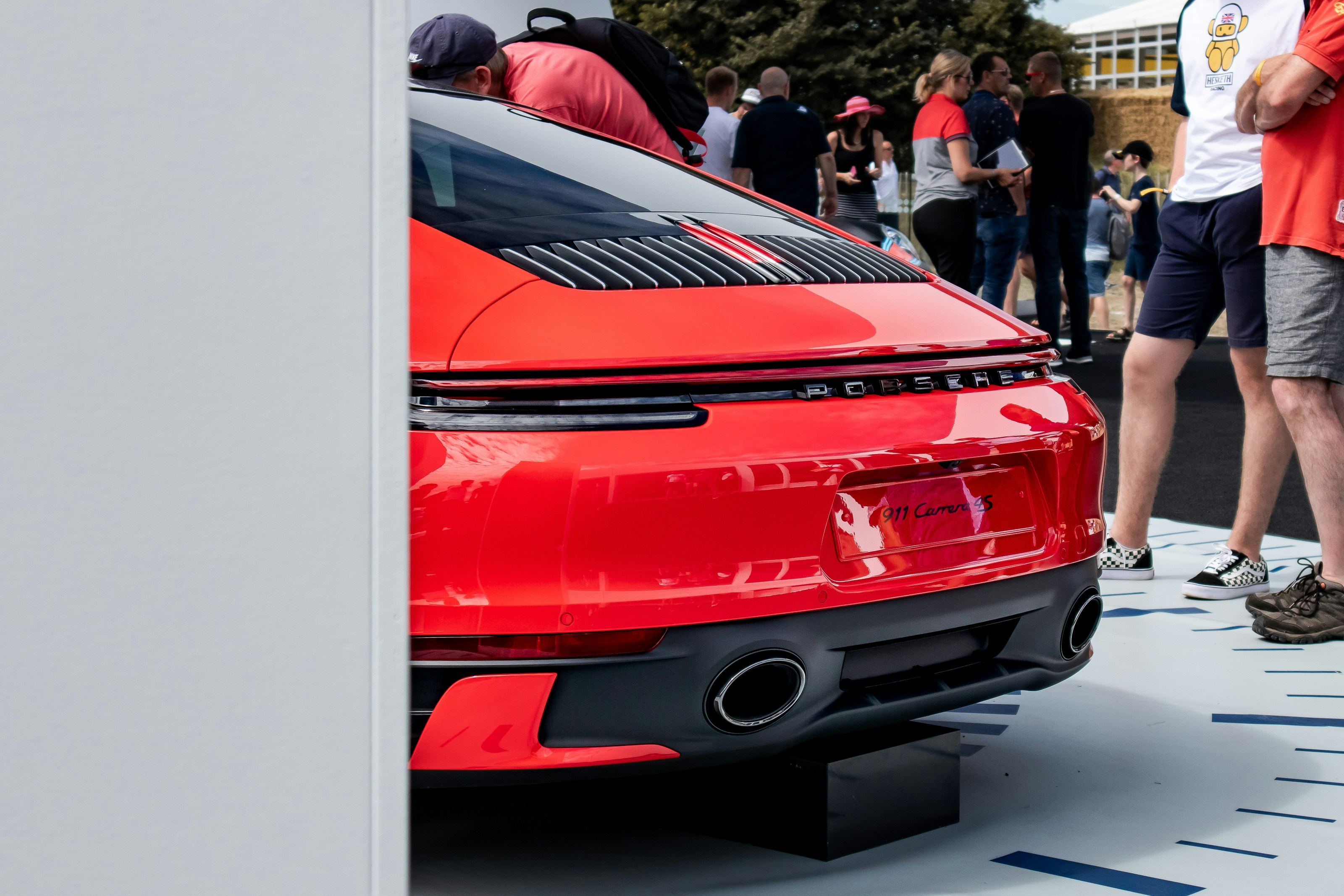 Un gruppo di persone in piedi intorno a un'auto rossa