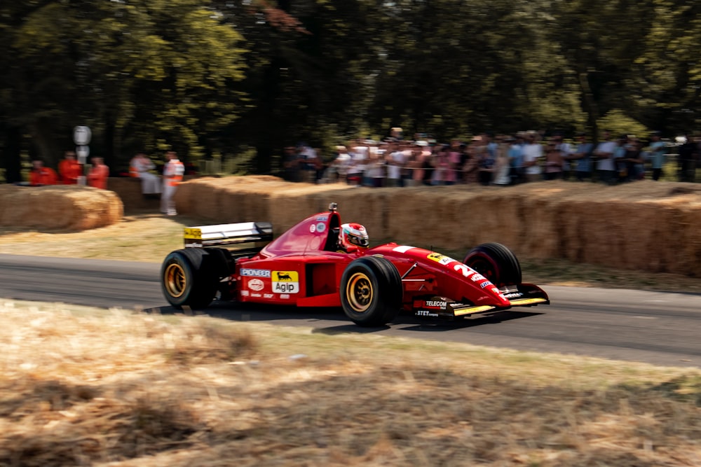 a man driving a red race car down a road