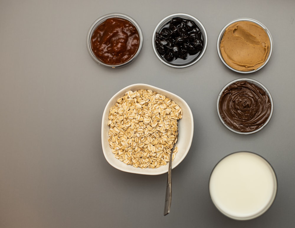 a bowl of cereal, milk, and other foodstuffs on a table