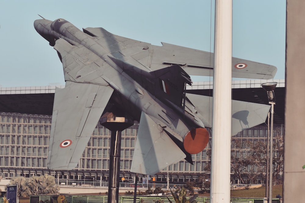 Un avión de combate está en exhibición frente a un edificio