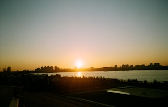 Sunset over the Maumee River with silhouettes of people enjoying the riverside park.