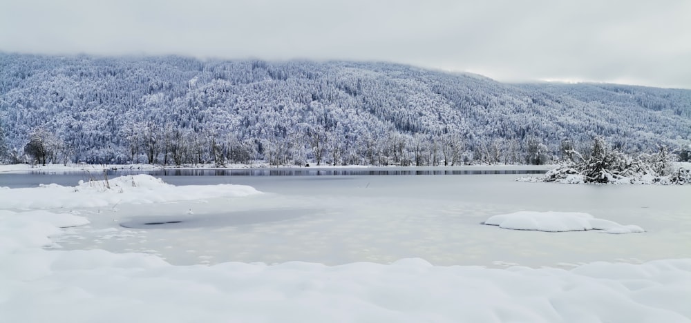 a frozen lake surrounded by snow covered mountains