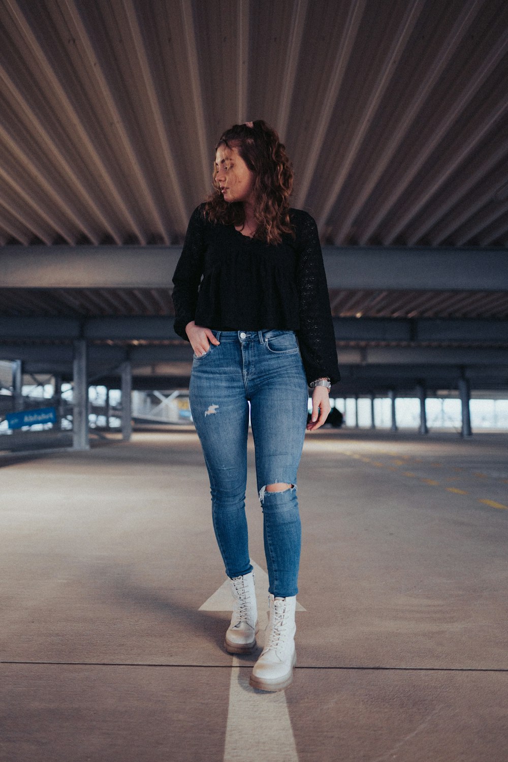 a woman standing in an empty parking garage