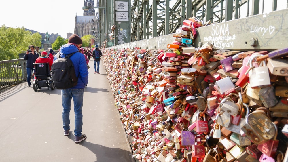 a man is walking past a wall covered with padlocks
