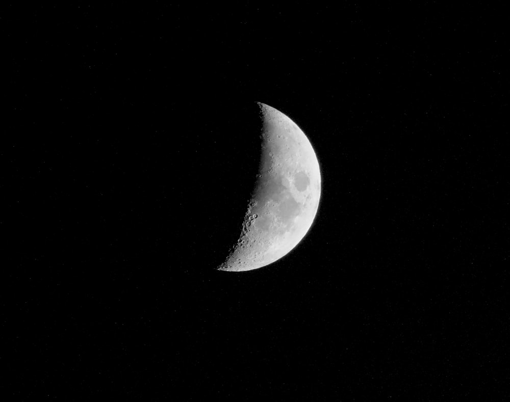 a half moon is seen in the dark sky