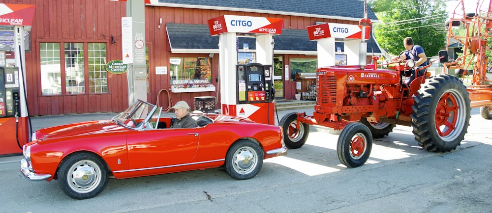 a red car parked in front of a gas station