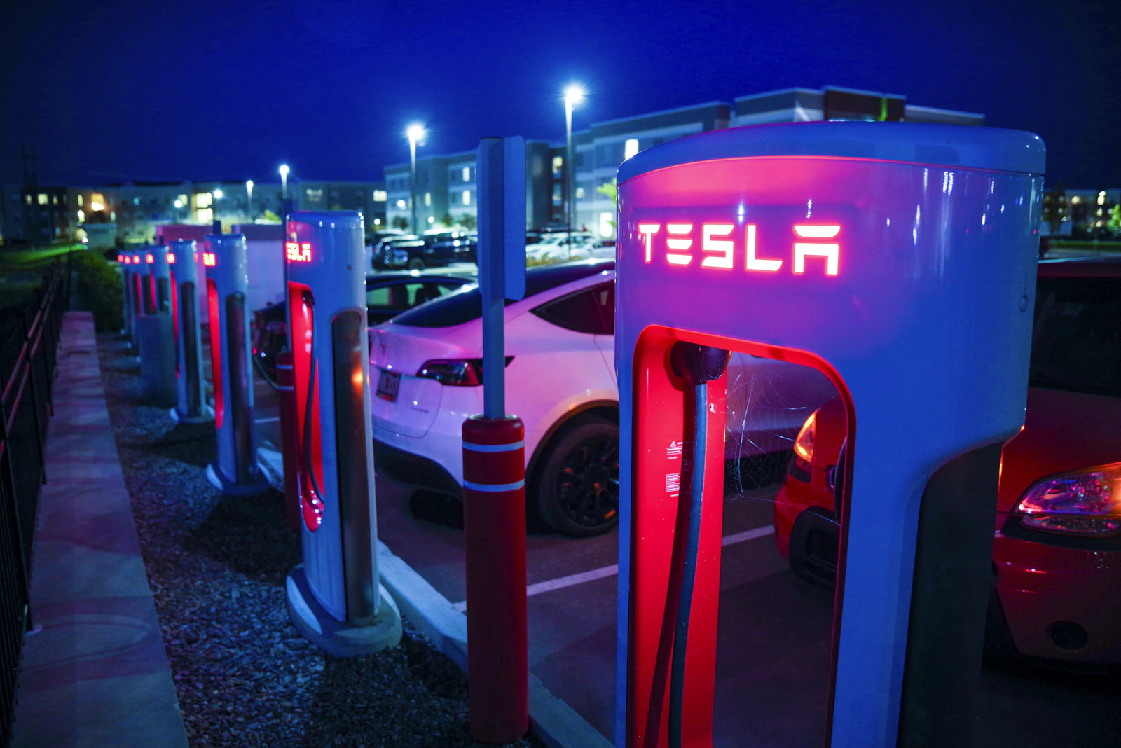 A row of EV charging stations at night, representing the network of stations OCPI Locations exposes