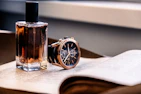 a bottle of perfume next to a watch on a table