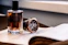 a bottle of perfume next to a watch on a table