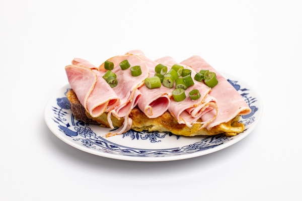 A plate with ham and peas on it