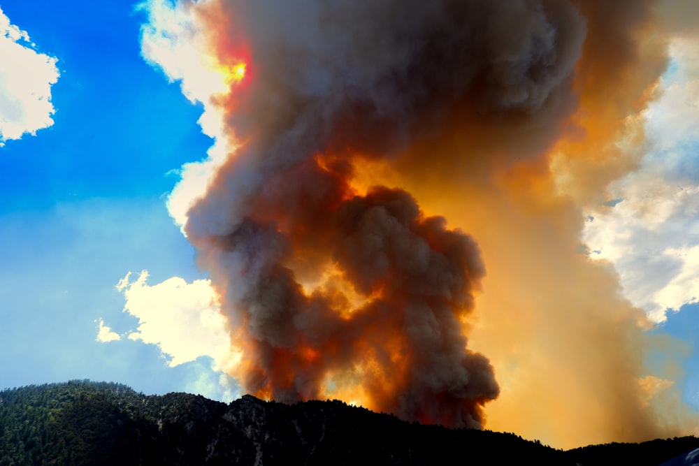 a large plume of smoke billowing out of a mountain