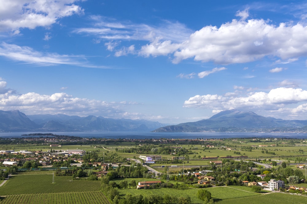 an aerial view of a rural area with a lake and mountains in the background