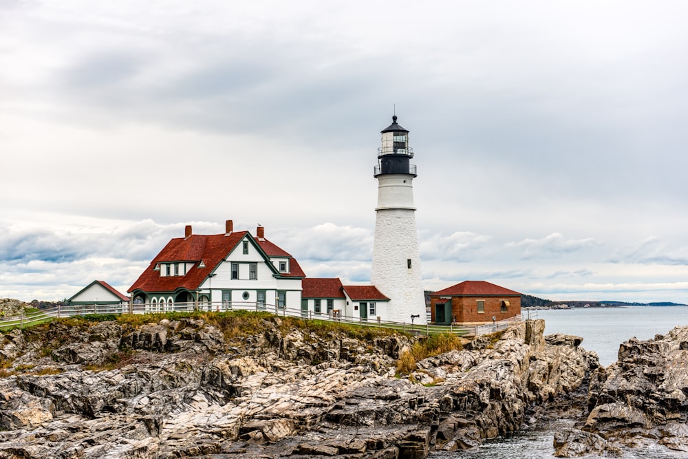a lighthouse on a rocky shore with a body of water in the background