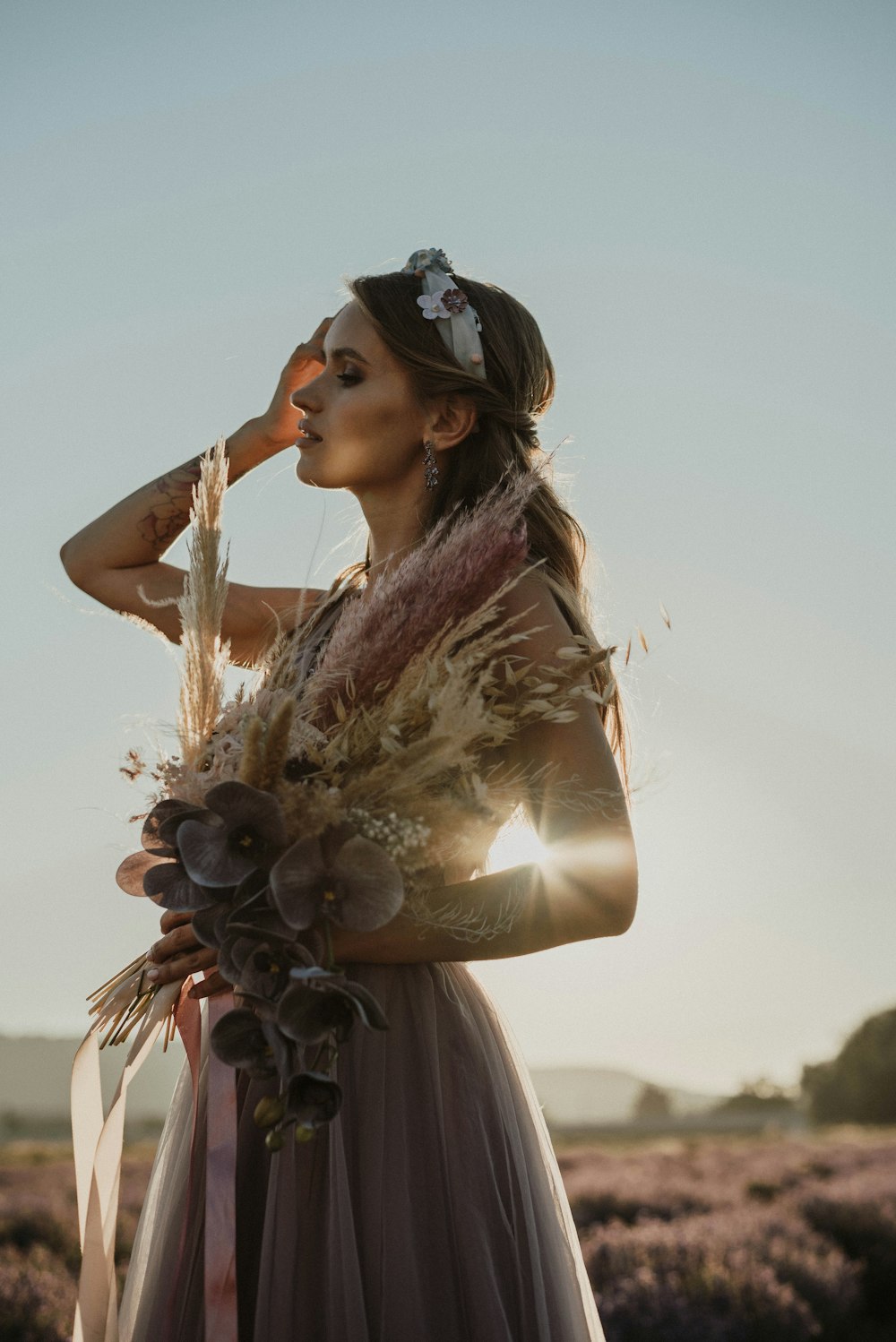 a woman standing in a field holding a bouquet of flowers