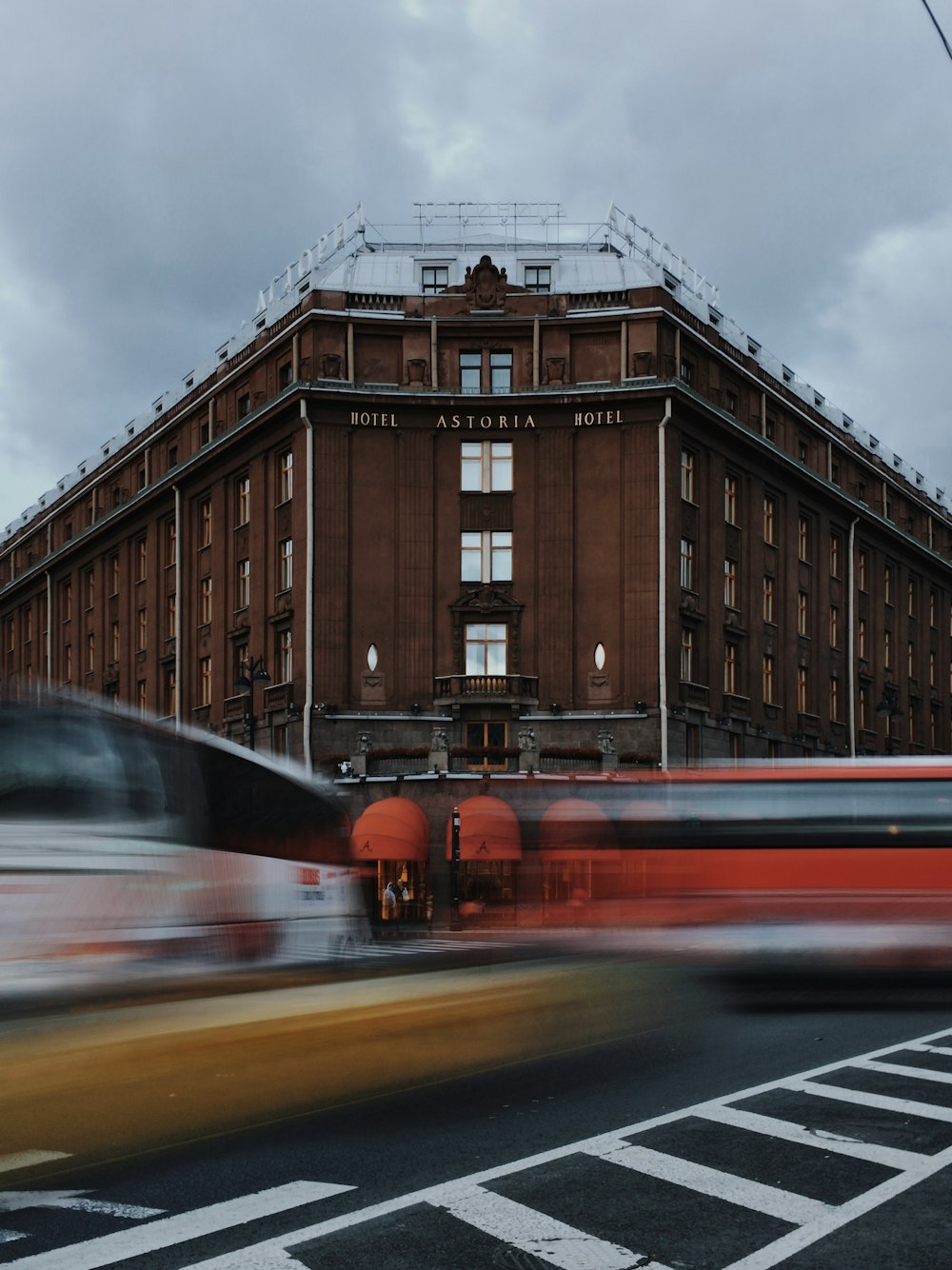 a red bus driving past a tall brown building