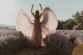 a woman standing in a lavender field with her arms in the air