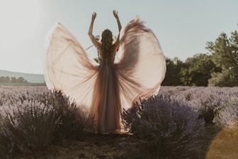 a woman standing in a lavender field with her arms in the air