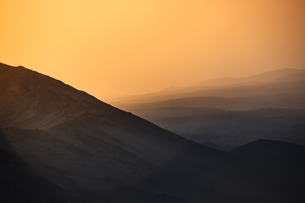 a person riding a horse on a hill at sunset