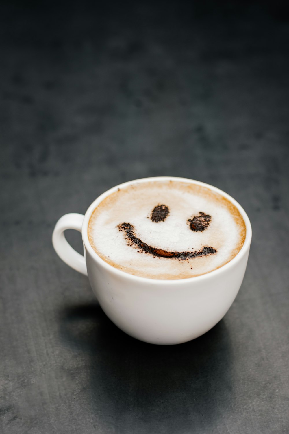 une tasse de café avec un visage souriant dessiné dessus