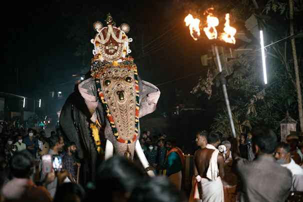 Elephant procession adorned in vibrant fabrics during an Indian festival.