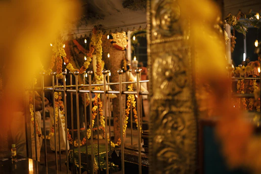 A serene temple courtyard bathed in golden sunlight with softly glowing diya lamps and fluttering marigold garlands.