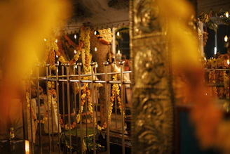 A serene temple courtyard bathed in golden morning light with flickering diyas and marigold garlands.