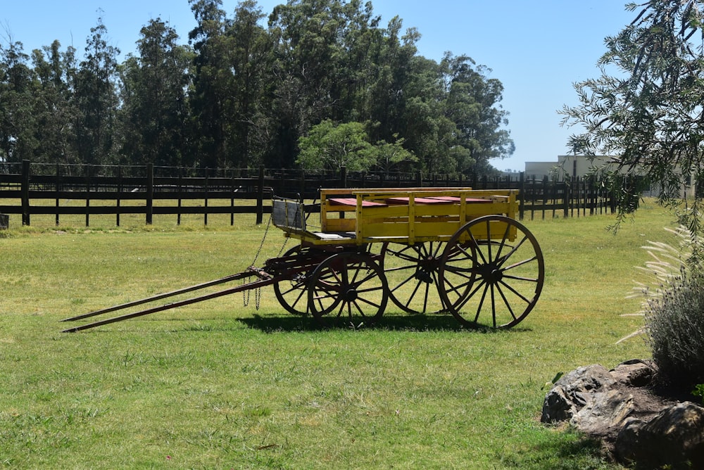 a yellow wagon sitting on top of a lush green field