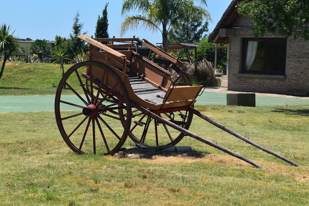 an old wooden wagon sitting on top of a lush green field