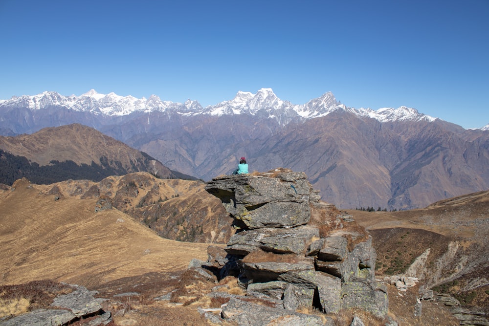 a person sitting on top of a large rock