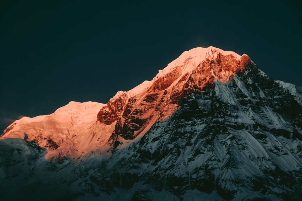 Une montagne enneigée avec un ciel sombre en arrière-plan